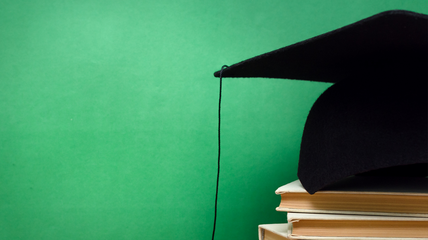 a graduation cap sits on top of a stack of books